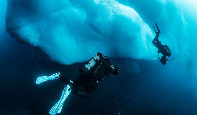 scuba divers in drysuits ice diving