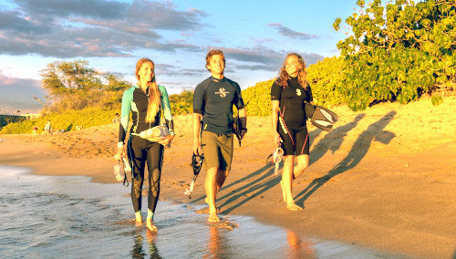 Three young snorkelers walking on the beach