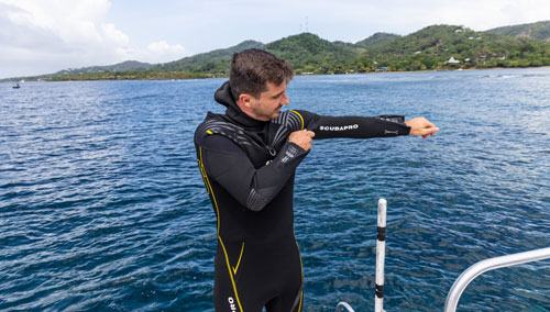 Man putting on the SCUBAPRO Definition 3mm Steamer