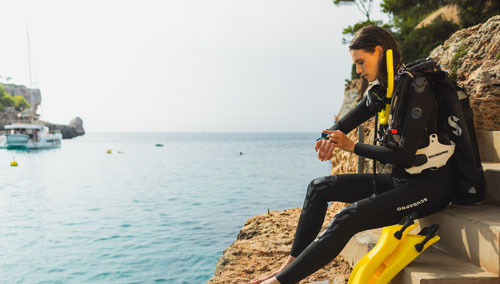 Woman in diving gear sitting on shore