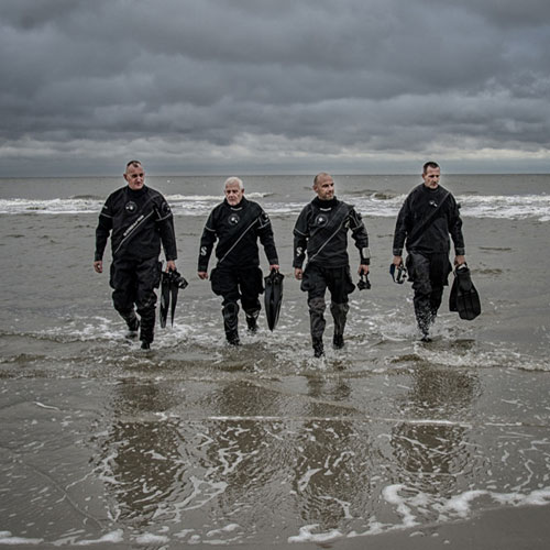 Four divers in SCUBAPRO gear walking in the surf