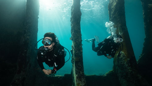 Two exploring underwater divers wearing SCUBAPRO gear